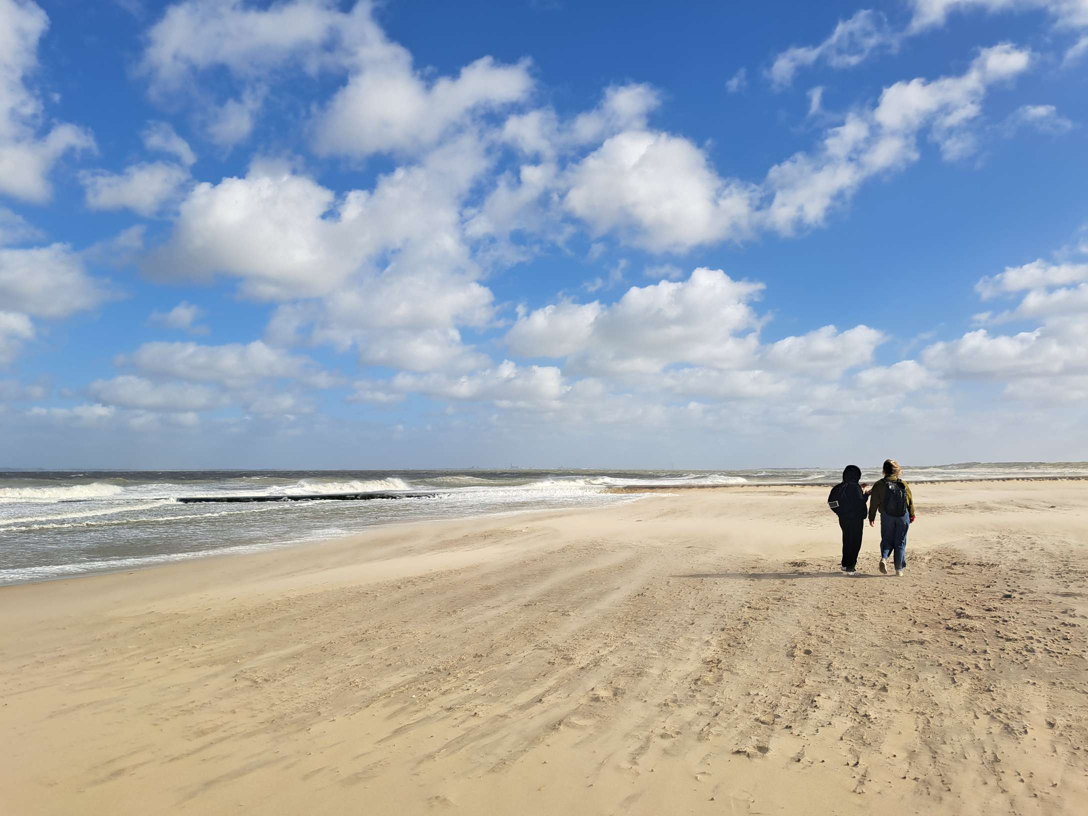 Veel wind op het strand, je ziet de zandstralen