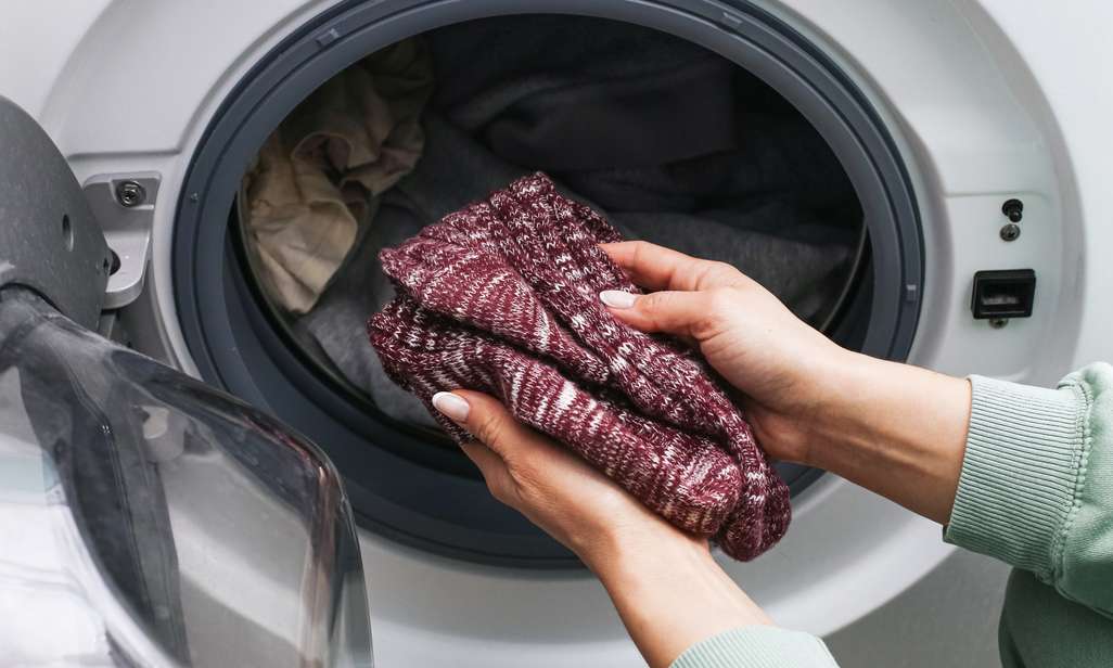Iemand stopt sokken in de wasmachine