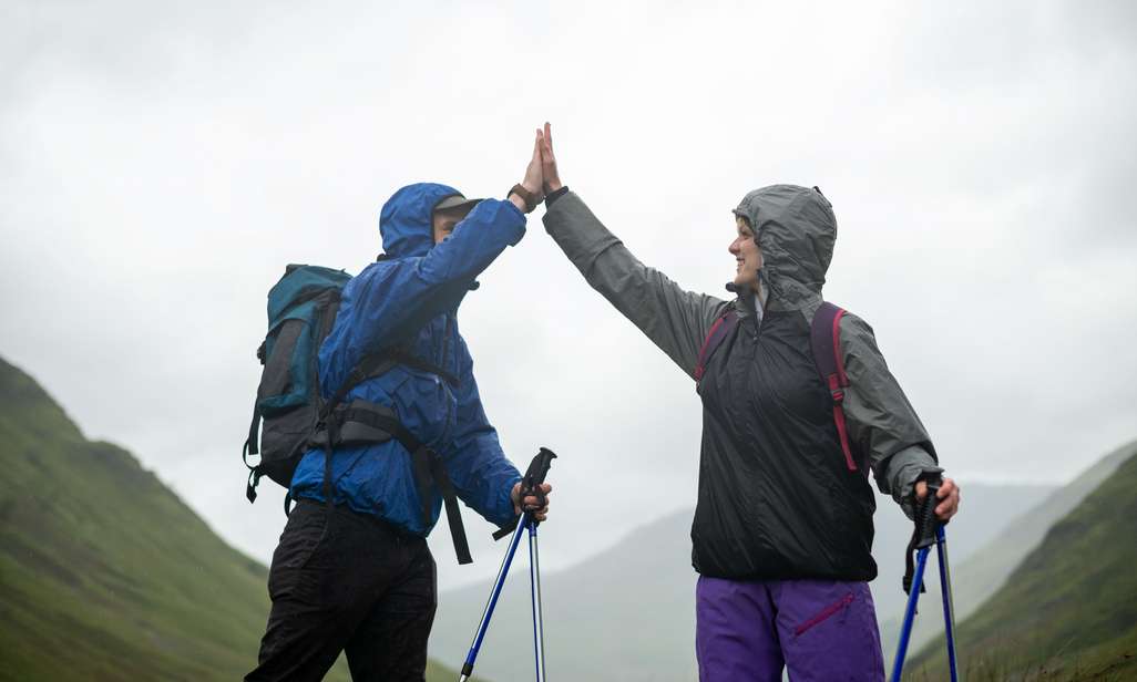 Twee mensen met een regenjas geven elkaar een high five